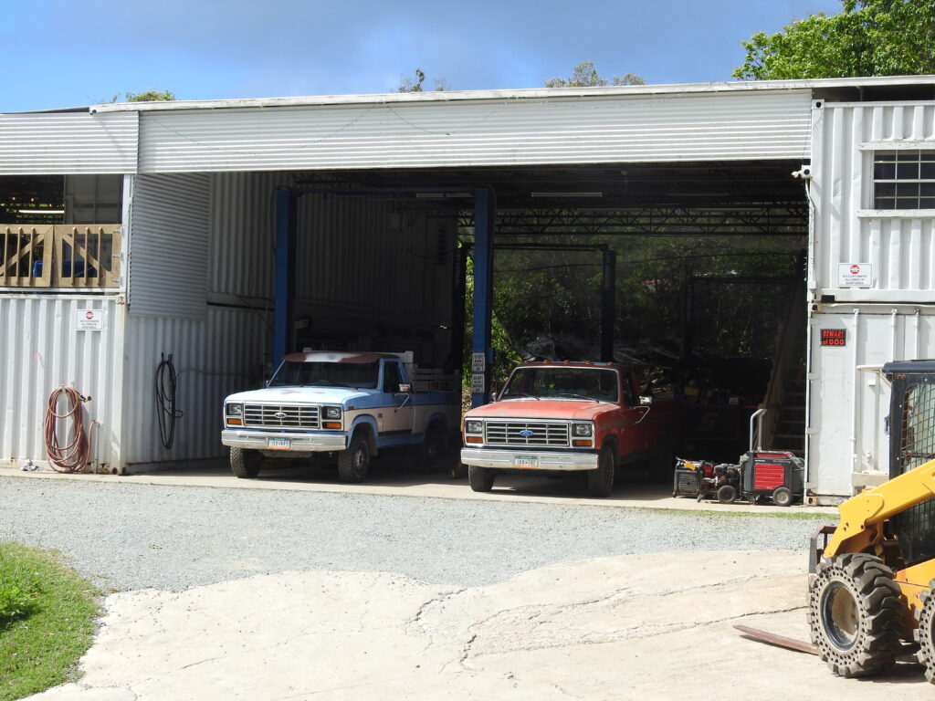 Two pickup trucks in an auto repair shop bay